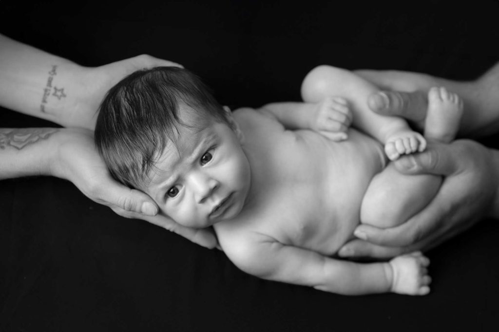 Newborn baby photographed in parents hands